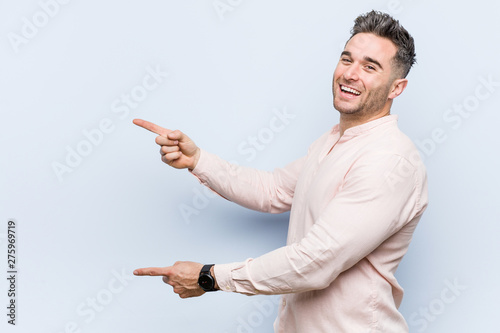 Young handsome cool man excited pointing with forefingers away.