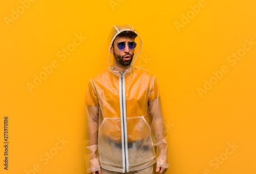 Young man wearing a rain coat thinking about an idea