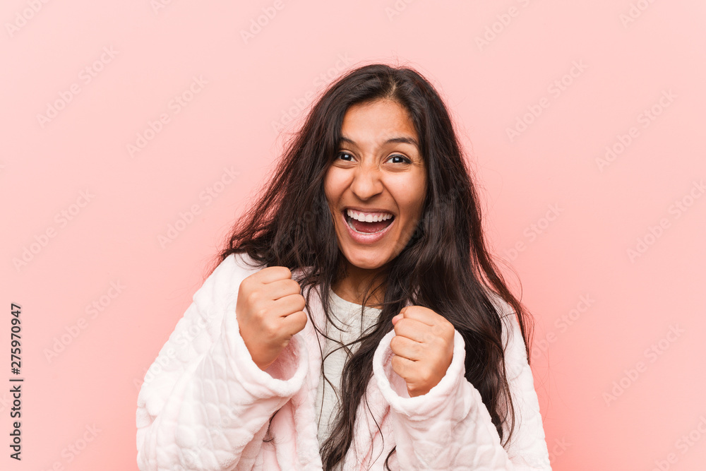 Young indian woman wearing pajama cheering carefree and excited. Victory concept.