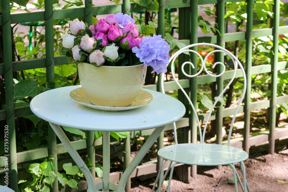 table and chairs in the garden with beautiful flowerpot full of colorful peony flowers table and chairs in the garden with beautiful flowerpot full of colorful peony flowers