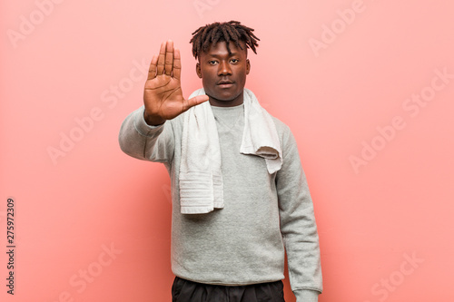 Young fitness african black man standing with outstretched hand showing stop sign, preventing you.