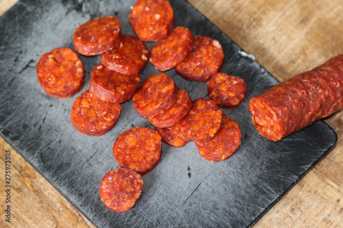 Fresh made Spanish pork chorizo sausages made with paprika, garlic, chilli and rosemary, sliced on a black cutting board photo