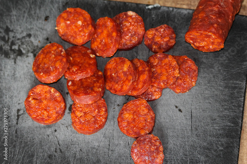 Fresh made Spanish pork chorizo sausages made with paprika, garlic, chilli and rosemary, sliced on a black cutting board photo