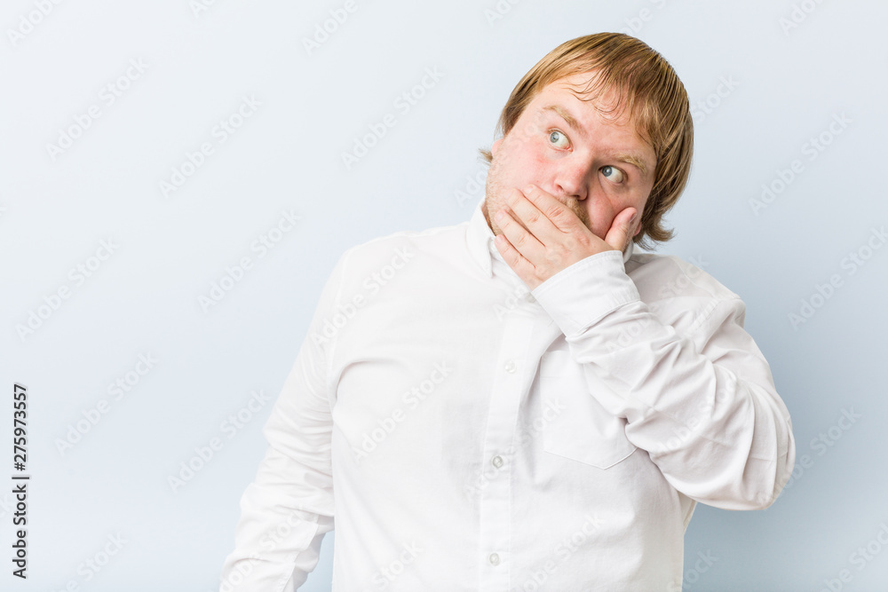 Young authentic redhead fat man thoughtful looking to a copy space covering mouth with hand. Young authentic redhead fat man thoughtful looking to a copy space covering mouth with hand.