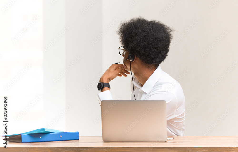 Young telemarketer black man from behind, looking back Young telemarketer black man from behind, looking back