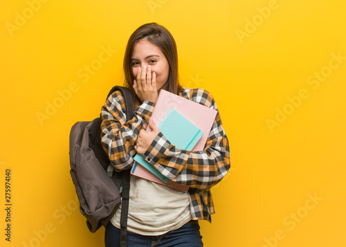 Young student woman laughing about something, covering mouth with hands