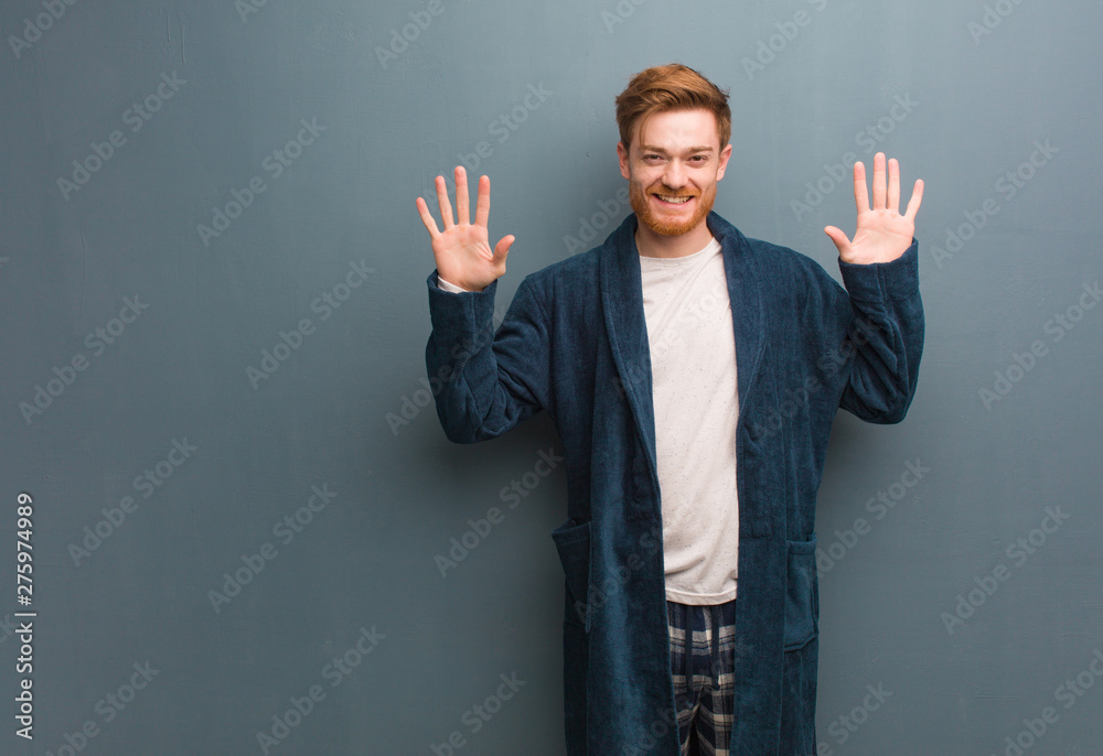 Young redhead man in pajama showing number ten - obrazy, fototapety, plakaty 