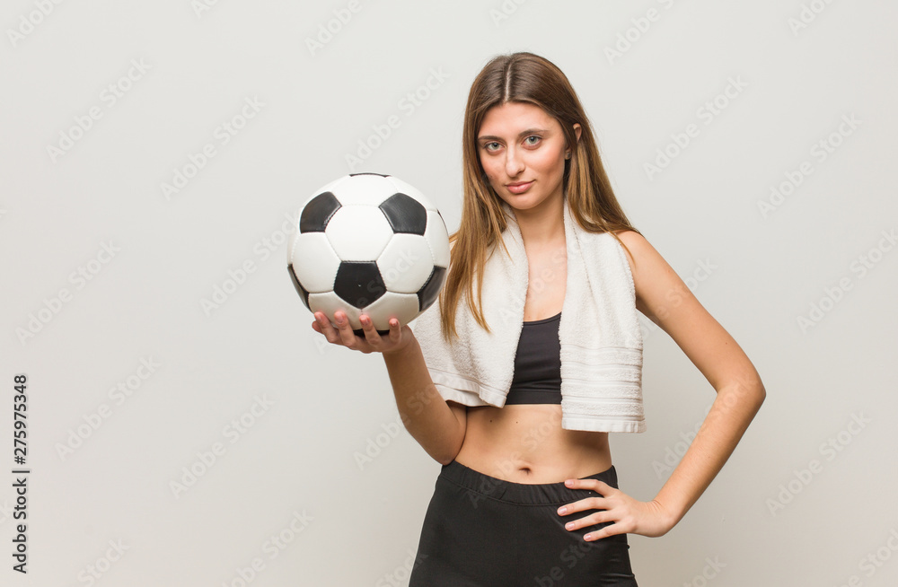 Young fitness russian woman looking straight ahead. Holding a soccer ball.