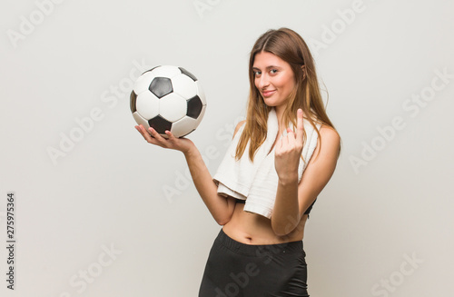 Young fitness russian woman inviting to come. Holding a soccer ball. © Asier