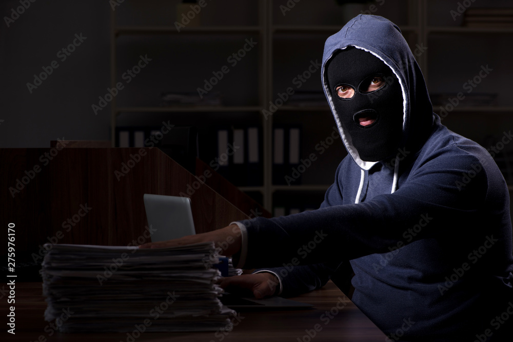 Male thief in balaclava in the office night time Male thief in balaclava in the office night time