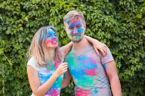 Holiday  holi and people concept - Smiling woman and man posing with multicolored powder on their faces