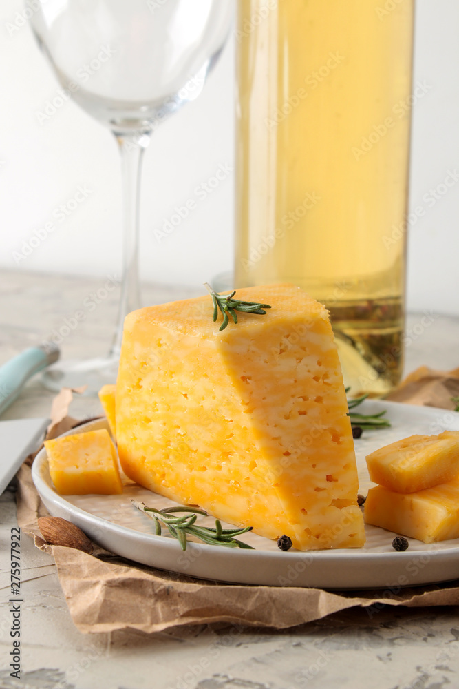 Slices of delicious marble cheese with a sprig of rosemary, honey and a cheese knife and white wine on a plate on a light concrete background. Slices of delicious marble cheese with a sprig of rosemary, honey and a cheese knife and white wine on a plate on a light concrete background.