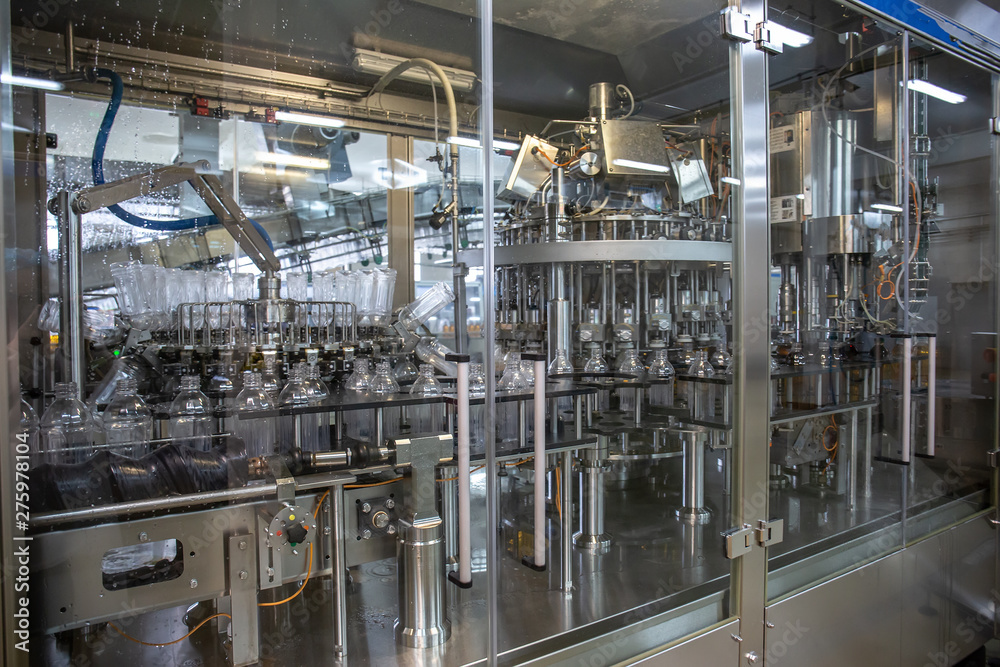 Plastic bottles inside industrial machine conveyor line or belt preparing for filling with drink. Water and juice bottling plant