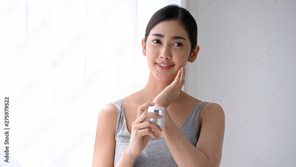 Beauty concept. Asian girl is applying cream on her face. Beauty concept. Asian girl is applying cream on her face.