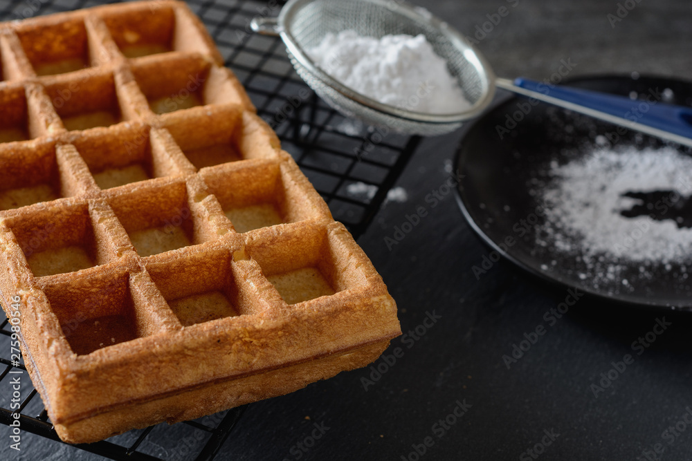 A large Viennese waffle cooked at home is on a black background and ready for filling