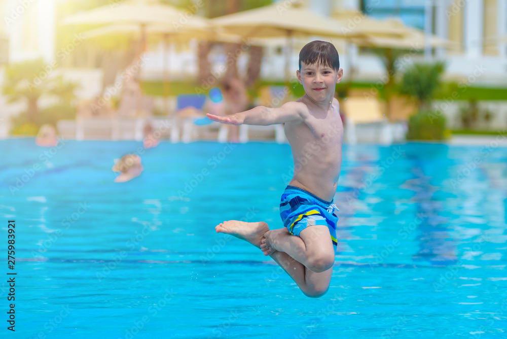 Caucasian boy having fun making fantastic jump into swimming pool at resort.  He is enjoying his summer vacations.