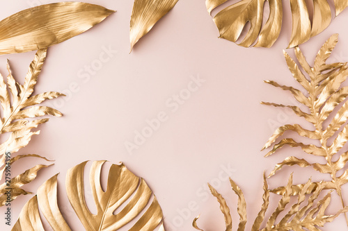 Flat lay frame of gold tropical palm leaves Monstera on pink background. Top view of minimal concept.