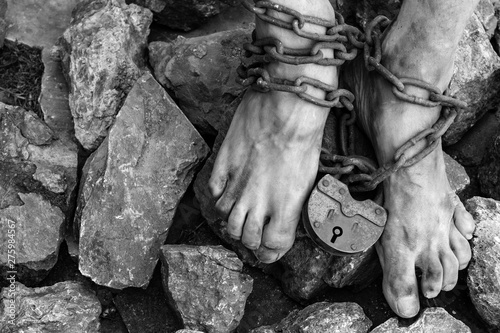 Chains with a lock on the legs of a slave amidst stones. Chains at the ankle. The symbol of slavery photo