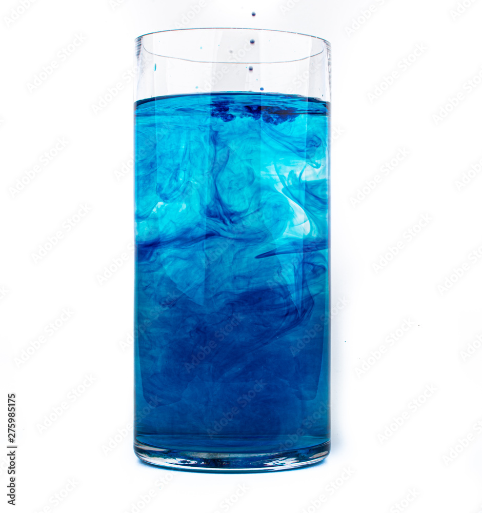 Blue food coloring diffuse in water inside glass with empty copyspace area for slogan or advertising text message, over isolated white background. Blue food coloring diffuse in water inside glass with empty copyspace area for slogan or advertising text message, over isolated white background.