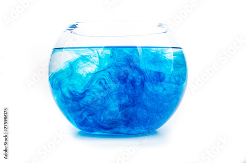 Blue food coloring diffuse in water inside round bowl with empty copyspace area for slogan or advertising text message, over isolated white background.