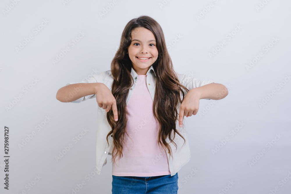 Little gilr standing over white studio background and pointing down her fingers. - Image Little gilr standing over white studio background and pointing down her fingers. - Image
