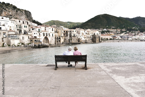 Cefalu, Province of Palermo, Sicily, Italy - Bench on the waterfront with a romantic couple