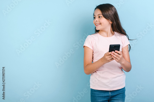 Girl holding mobile phone with happy looking sideaway. - Image