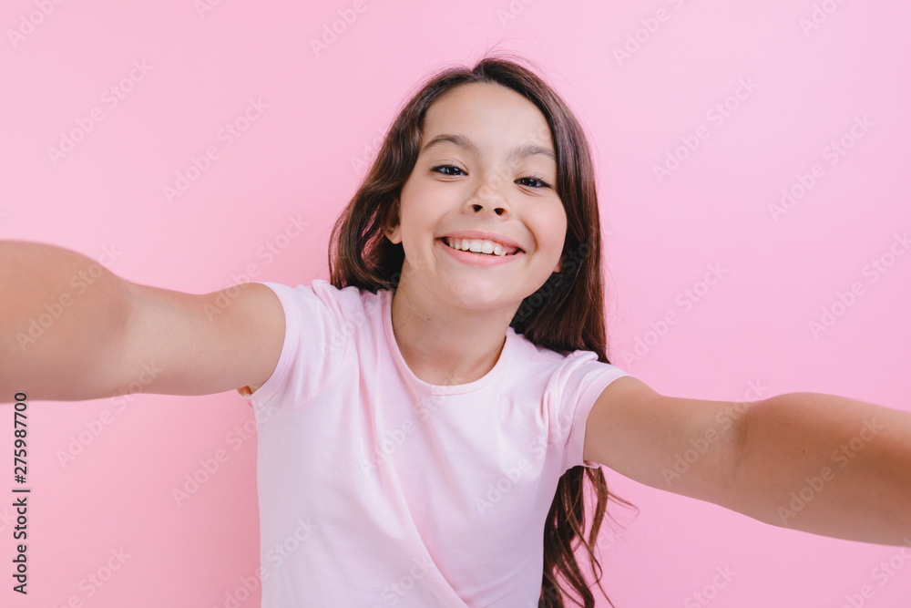 Closeup portrait of a cheerful girl over pink studio background with straightening hands Closeup portrait of a cheerful girl over pink studio background with straightening hands