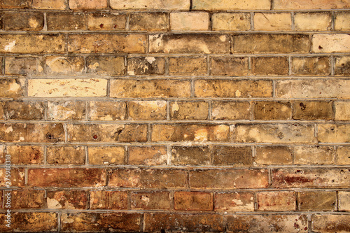 Aged partially crumbled brown brick wall background