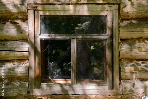 Old window in an abandoned log house on a sunny summer day