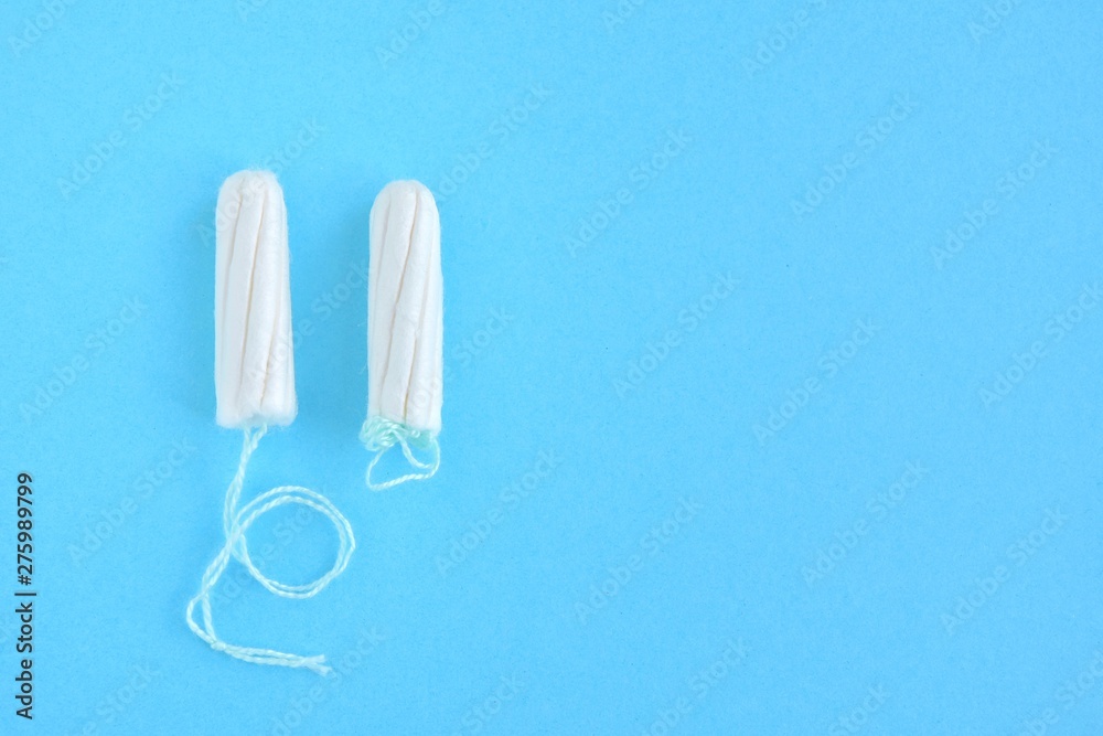 Two cotton tampons for women monthly menstruation with selective focus on blue background. Soft white tampon for female period days on neutral backdrop with empty space for text. Healthcare Two cotton tampons for women monthly menstruation with selective focus on blue background. Soft white tampon for female period days on neutral backdrop with empty space for text. Healthcare