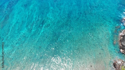 Top view of the turquoise sea. Sunlight shimmers, reflects the rays from the sea.