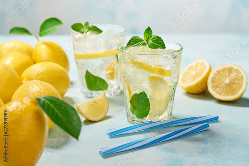 two glasses of lemonade with fresh lemon on turquoise background