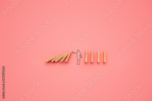 Shape of a man stopping dominos from falling