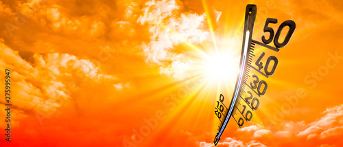 Hot summer or heat wave background, glowing sun on orange sky with thermometer photo