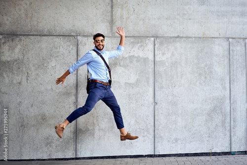 Portrait of young businessman jumping in joy and looking at camera