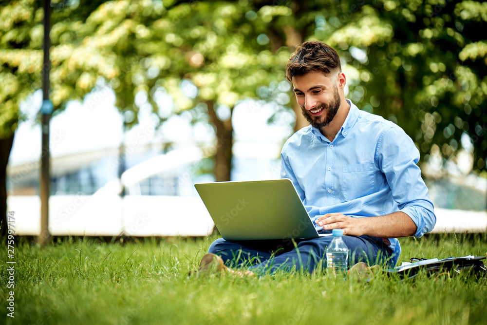 Portrait of young businessman sitting in the park and working on laptop Portrait of young businessman sitting in the park and working on laptop