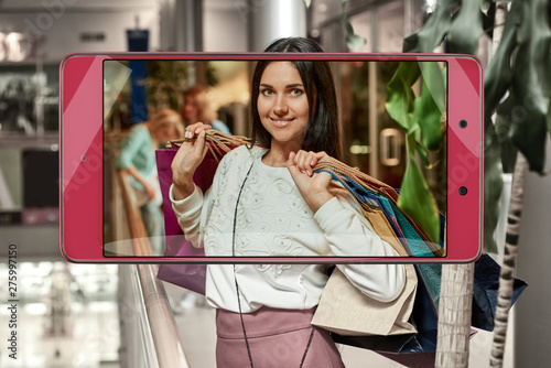 Photo of attractive shopping woman with bags, concept of new features in smartphone s camera