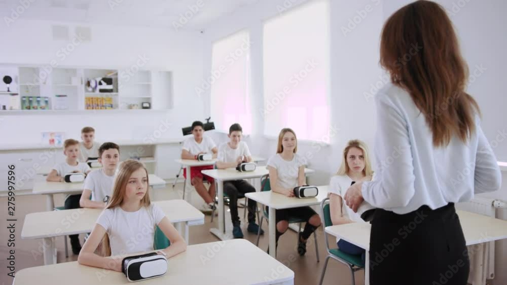 Amazing future computer science class in a schoo. Students listening to their teacher explaining how virtual reality headsets work. Amazing future computer science class in a schoo. Students listening to their teacher explaining how virtual reality headsets work.