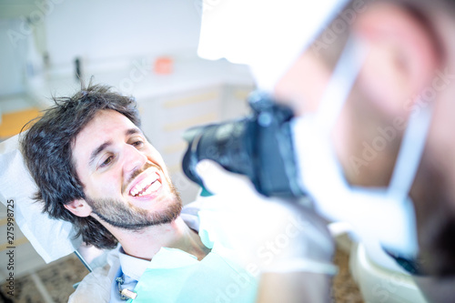 Fotografo odontoiatra per la fotografia della dentatura d un paziente sdraiato sulla poltrona. photo