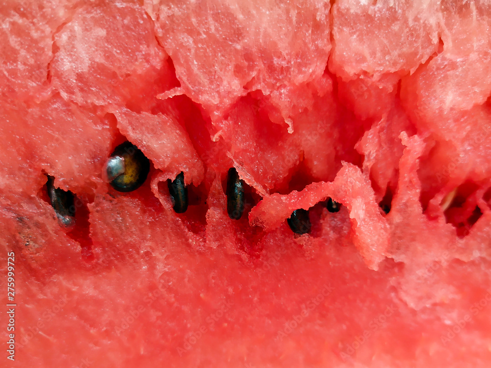 Photo of the pulp of ripe red watermelon with black seeds