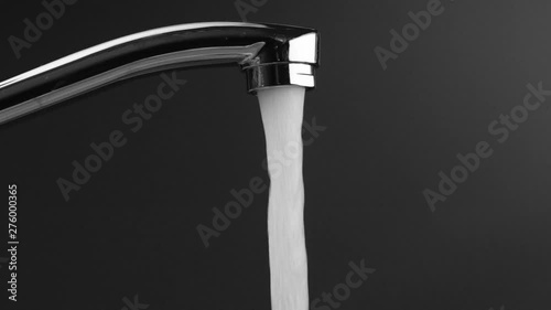 someone turns on a water tap, water pours on a gray background