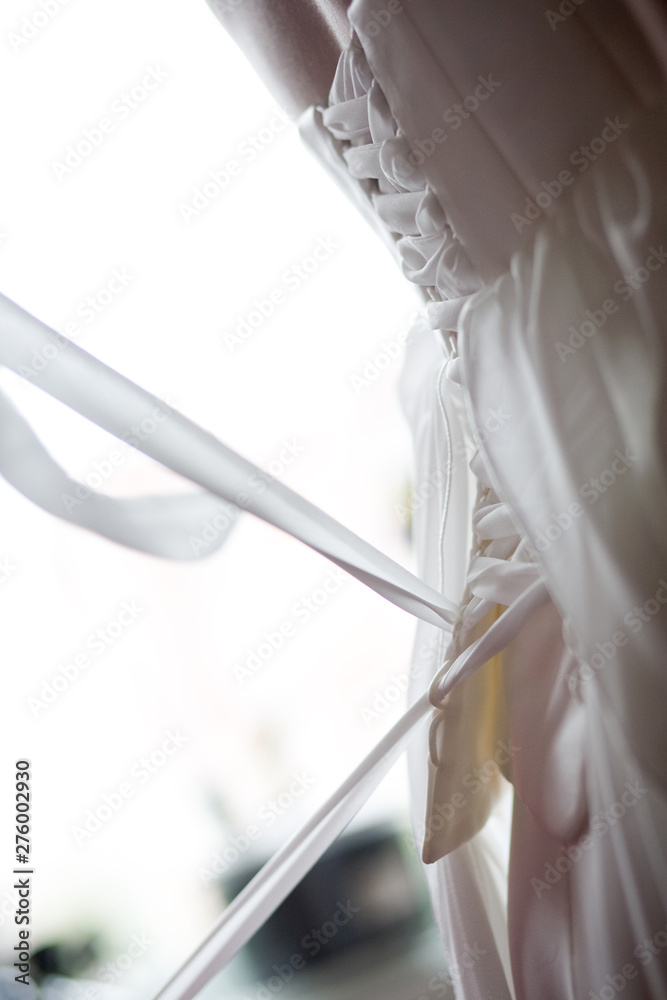Bride from the back. Lacing the wedding dress.