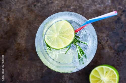 Gin and tonic cocktail with lime and rosemary - refreshing summer alkoholic drink - overhead view