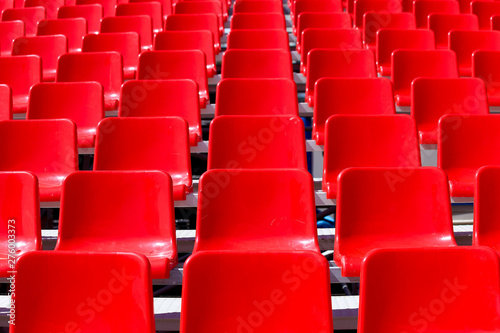 Rows of the red plastic chairs in perspective as a background. Photo with selective focus 