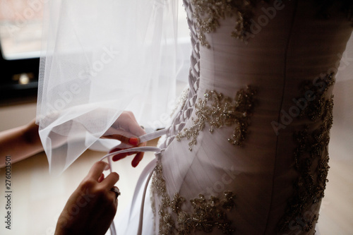 Bride from the back. Lacing the wedding dress.