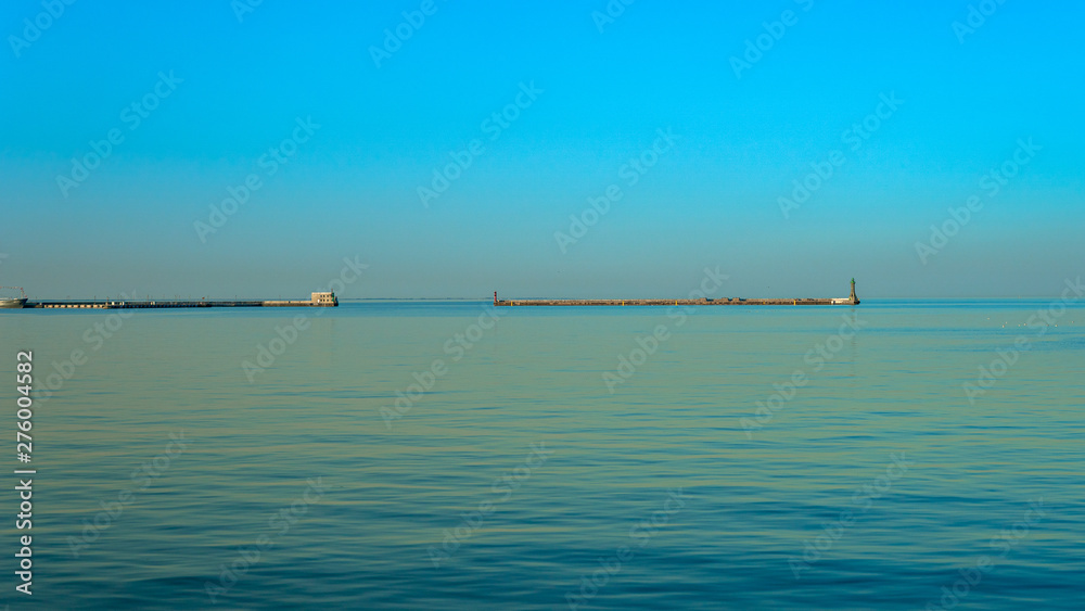 Beautiful view of the bay at sunset. Clear sky and calm sea in light blue color.