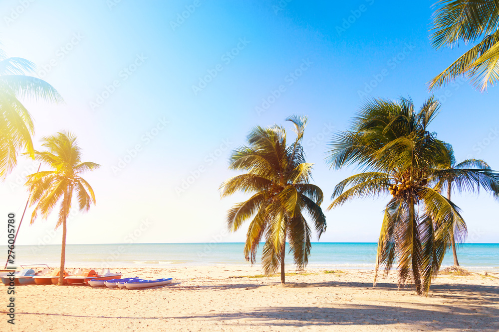 The tropical beach of Varadero in Cuba with sailboats and palm trees on a summer day sunset with turquoise water. Vacation background.