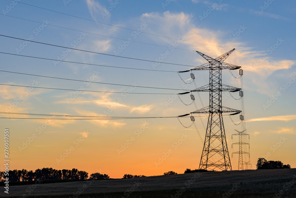 Electricity pylons and high voltage power lines at sunset - obrazy, fototapety, plakaty 
