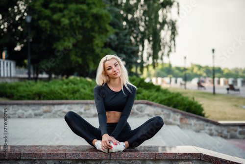 Healthy sports lifestyle. Young beautiful woman in a sports wear sit in city park